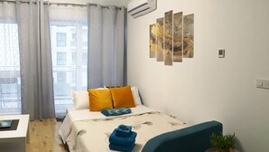 Un dormitorio con una cama, una mesita de noche con una planta y una ventana con cortinas.
