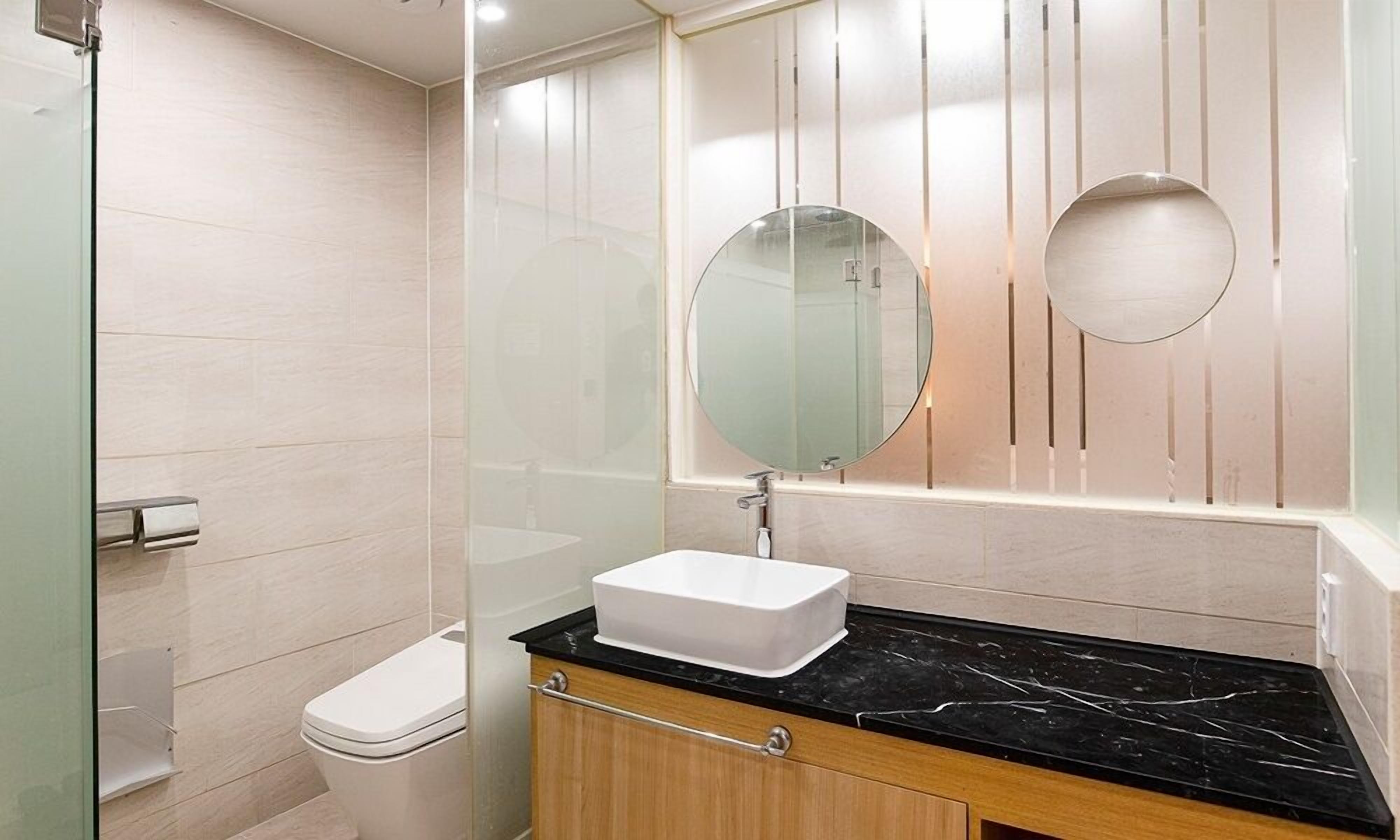 A bathroom with a white toilet, a rectangular sink with a black countertop, and a mirror above the sink.