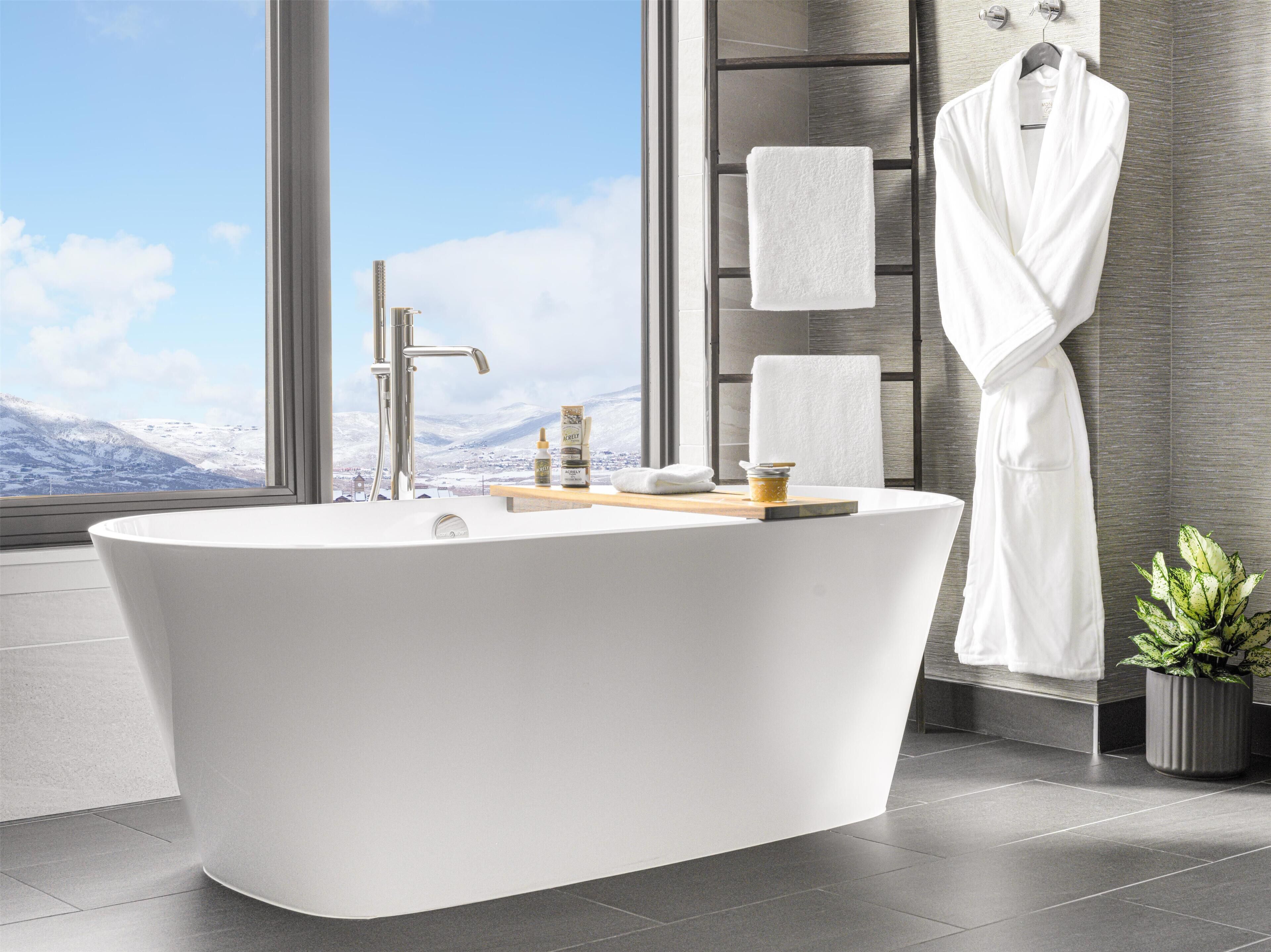 A modern bathroom with a freestanding bathtub, a wooden vanity, and a large window offering a mountain view.