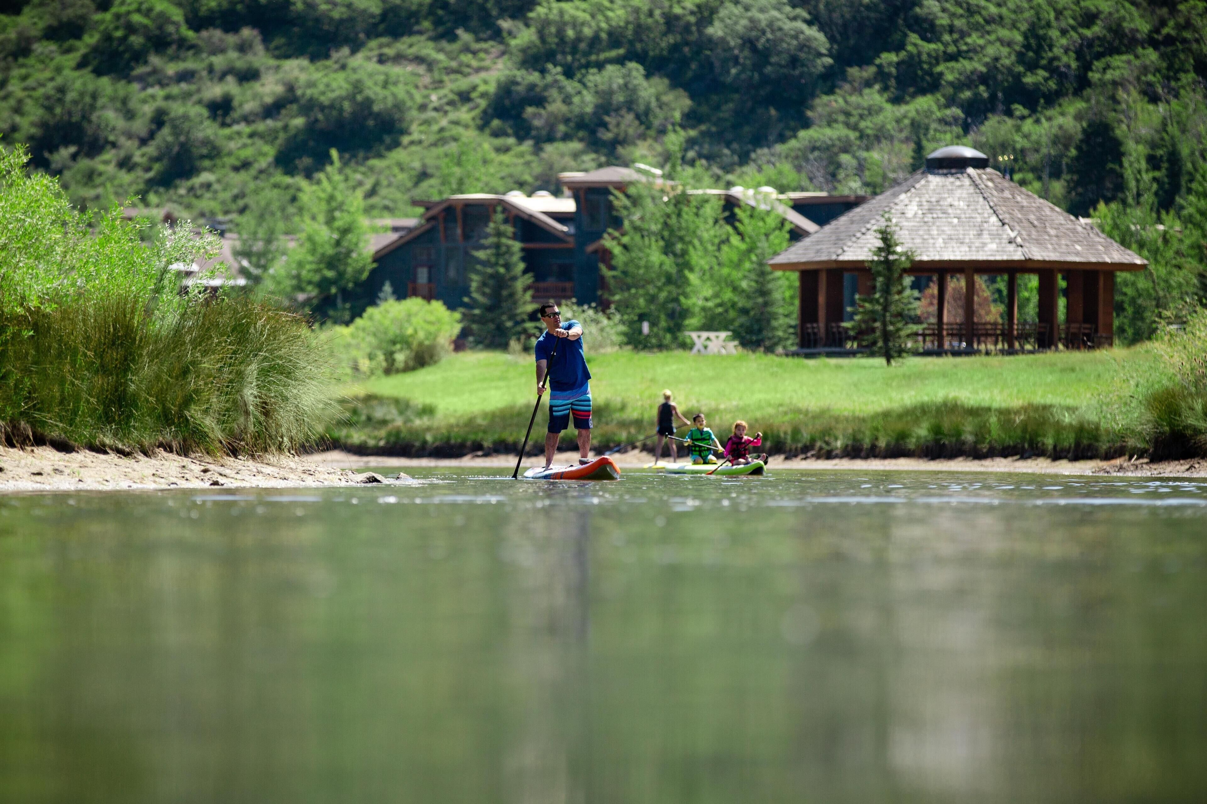A river with paddleboards, a gazebo, and houses in the background.