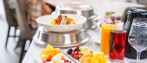Un bufé de desayuno con diversas frutas y bebidas.