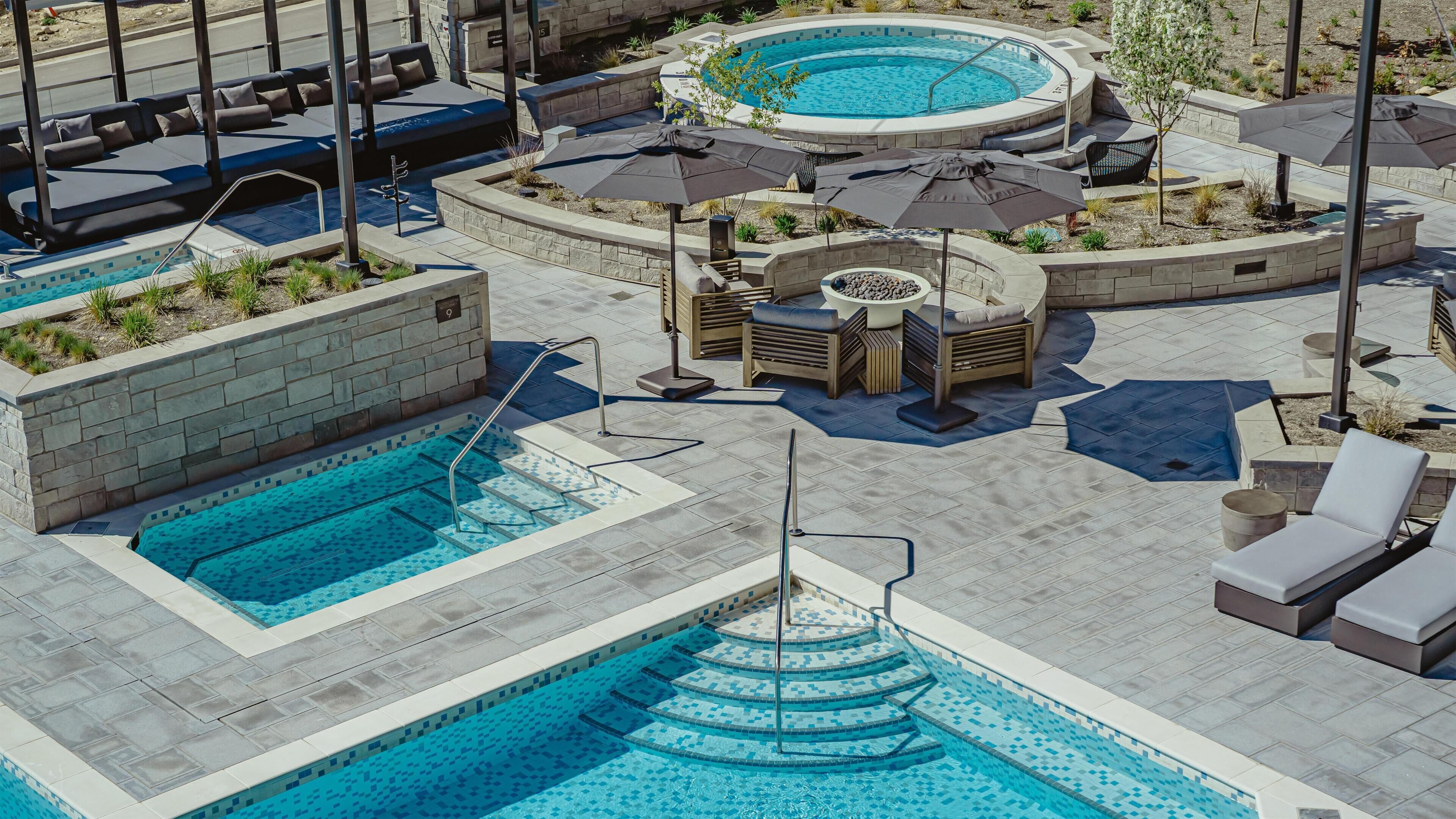 A multi-level outdoor pool area with various seating options and a hot tub.