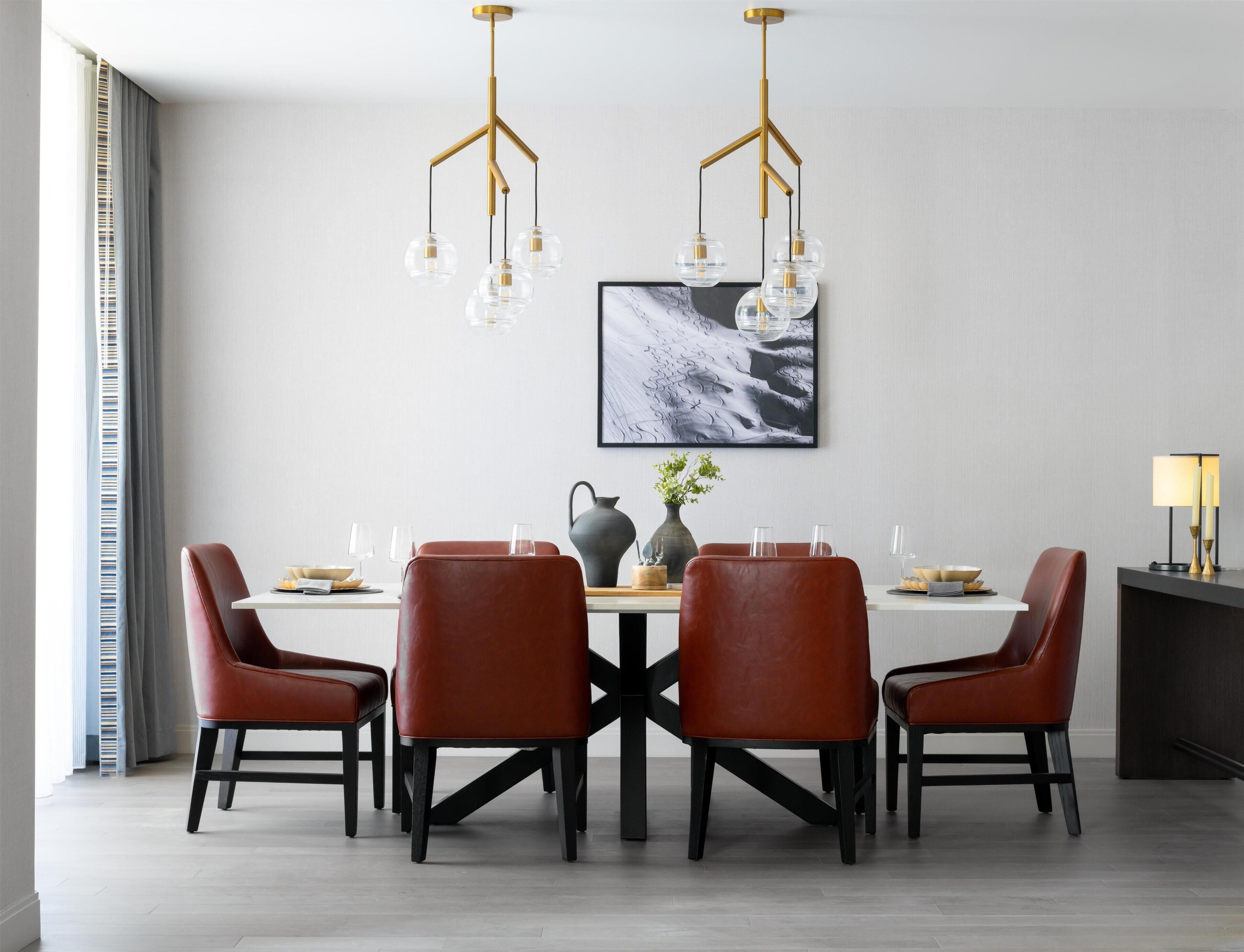 A dining area with a table, chairs, a vase, and a painting on the wall.