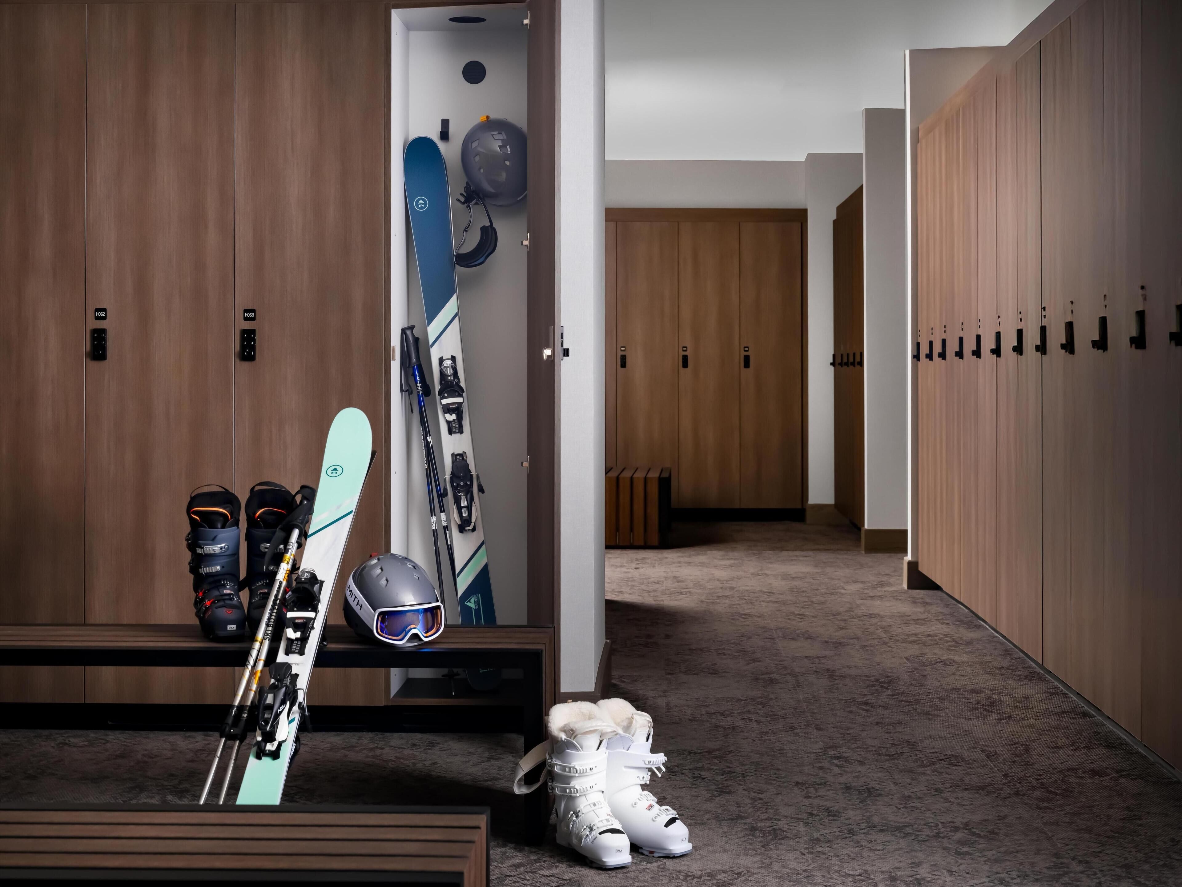Un couloir avec des casiers, des paires de skis et du matériel de ski.