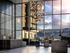 A modern hotel lobby with large windows, a chandelier, and a reception desk. - Grand Hyatt Deer Valley (Park City)