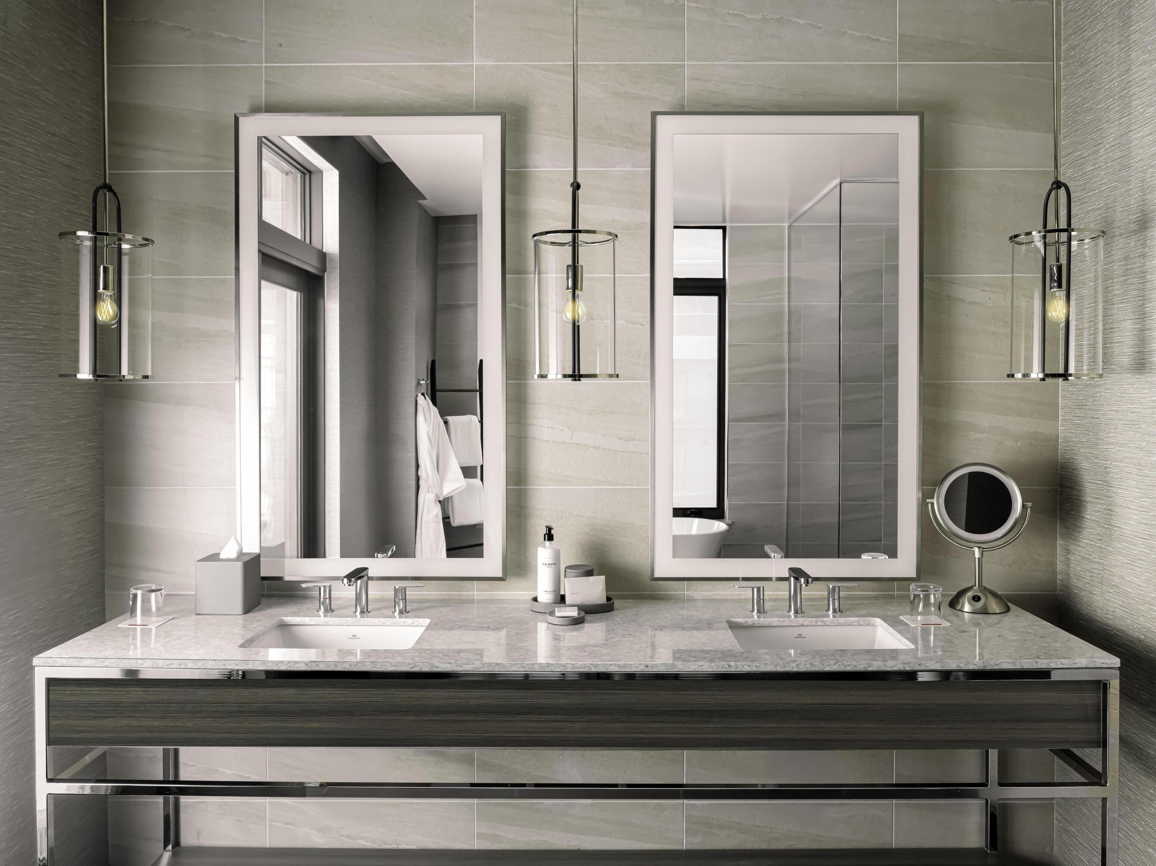 A modern bathroom with a double sink vanity, large mirrors, and pendant lighting.