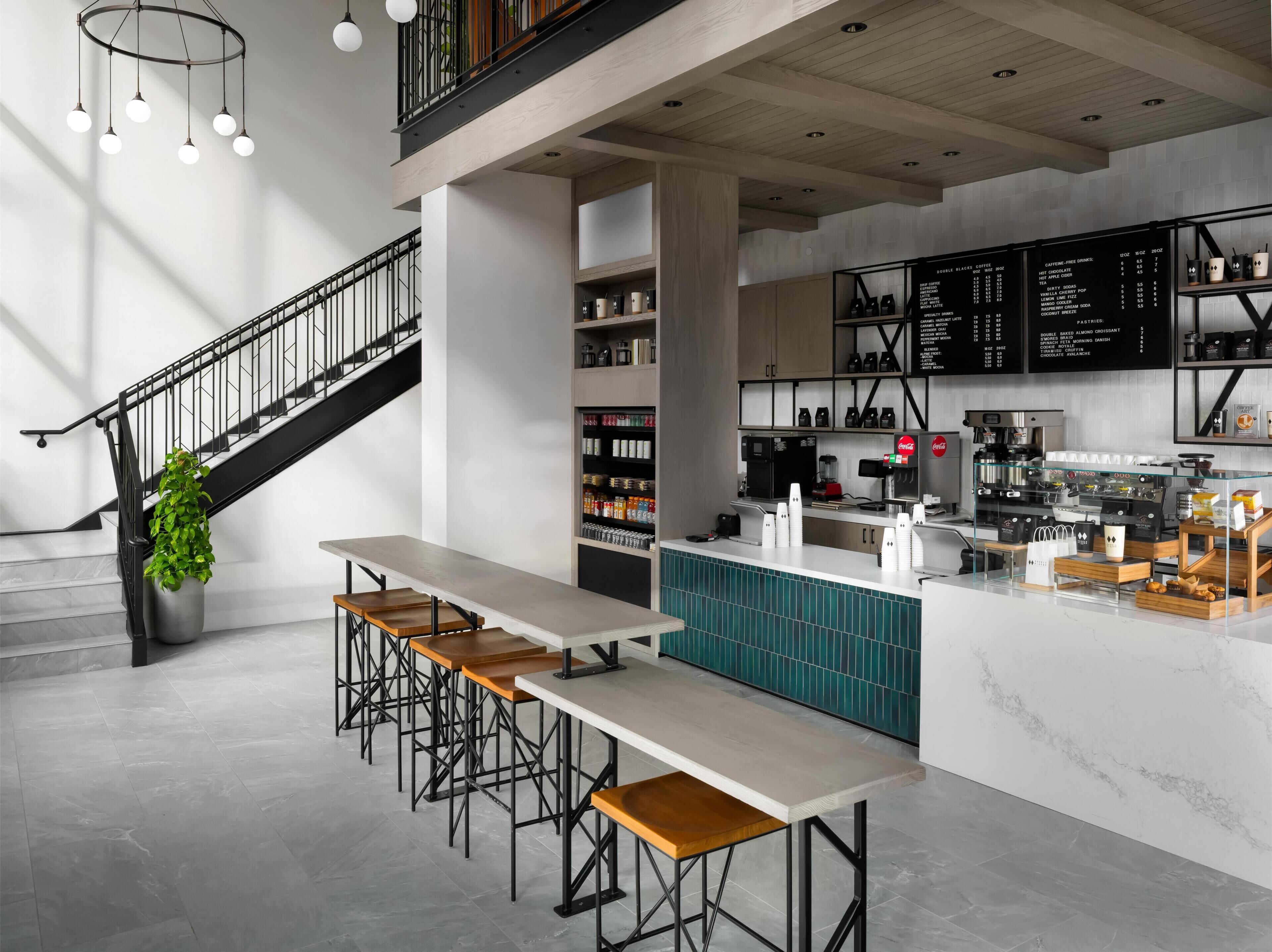 A modern café interior with a staircase, seating area, and a menu board.