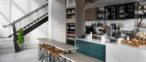 A modern café interior with a staircase, seating area, and a menu board.