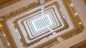 Un atrio moderno con un diseño geométrico de techo de vidrio y varios niveles de balcones.