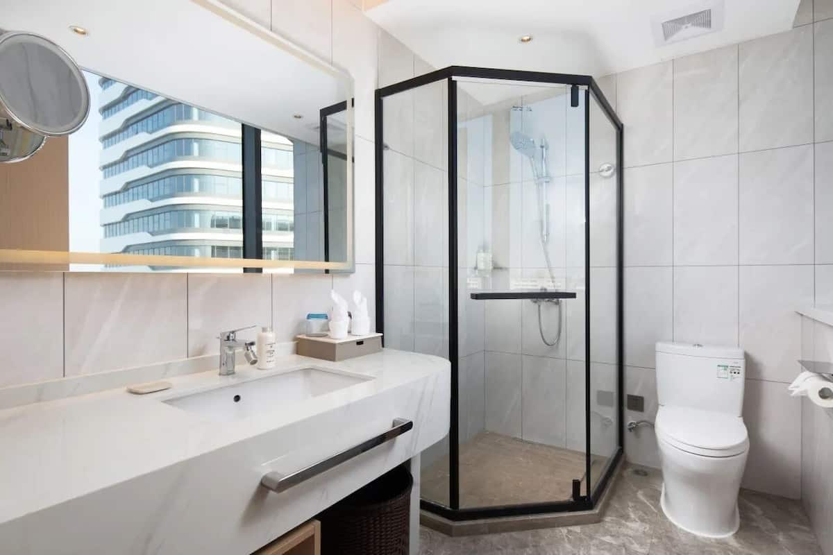 A modern bathroom with a glass-enclosed shower, a white sink with a mirror, and a toilet.