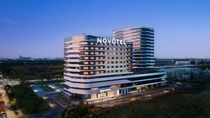 Un hotel Novotel de diseño moderno, con varios pisos y una estructura curva destacada.