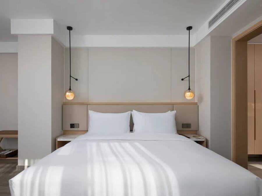 Una habitación de hotel moderna con una cama grande, dos mesitas de noche y un armario de madera.