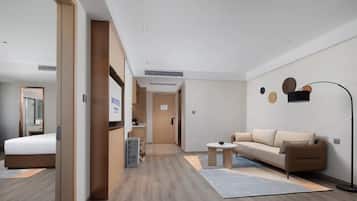 A modern hotel room with a bed, a sofa, a small table, and a floor lamp.