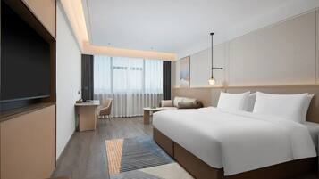 A modern hotel room with a large bed, a desk, a chair, and a TV.