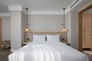 A modern hotel room with a large bed, two bedside tables, and pendant lighting.