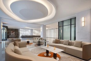 A modern hotel lobby with a curved ceiling, large windows, and a seating area with sofas and tables. - Novotel Jiaxing Port Area (Jiaxing)