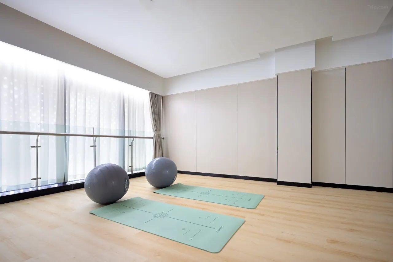 A spacious room with large windows, a wooden floor, two exercise balls, and two yoga mats.