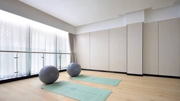 A spacious room with large windows, a wooden floor, two exercise balls, and two yoga mats.
