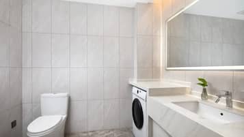 Un baño moderno con inodoro, lavadora y lavabo con espejo.