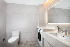 A modern bathroom with a toilet, washing machine, and a sink with a mirror. - Novotel Jiaxing Port Area (Jiaxing)