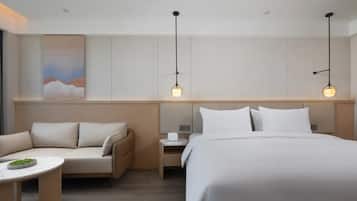 Una habitación de hotel con una cama, un sofá, una mesita y dos lámparas colgantes.