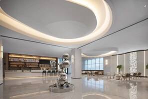 A modern lobby with a central sculpture, a gourmet bar, and seating areas. - Novotel Jiaxing Port Area (Jiaxing)