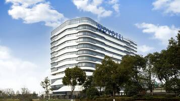Een modern hotelgebouw met een gebogen gevel en de naam 'NOVOTEL' bovenaan.