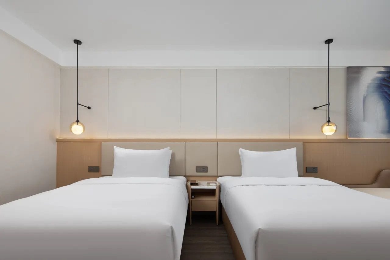 Habitación de hotel con dos camas, una mesita de noche y un cuadro en la pared.