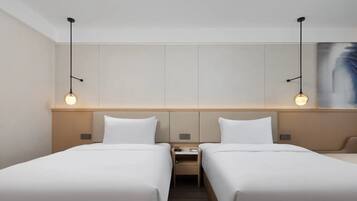 Habitación de hotel con dos camas, una mesita de noche y un cuadro en la pared.