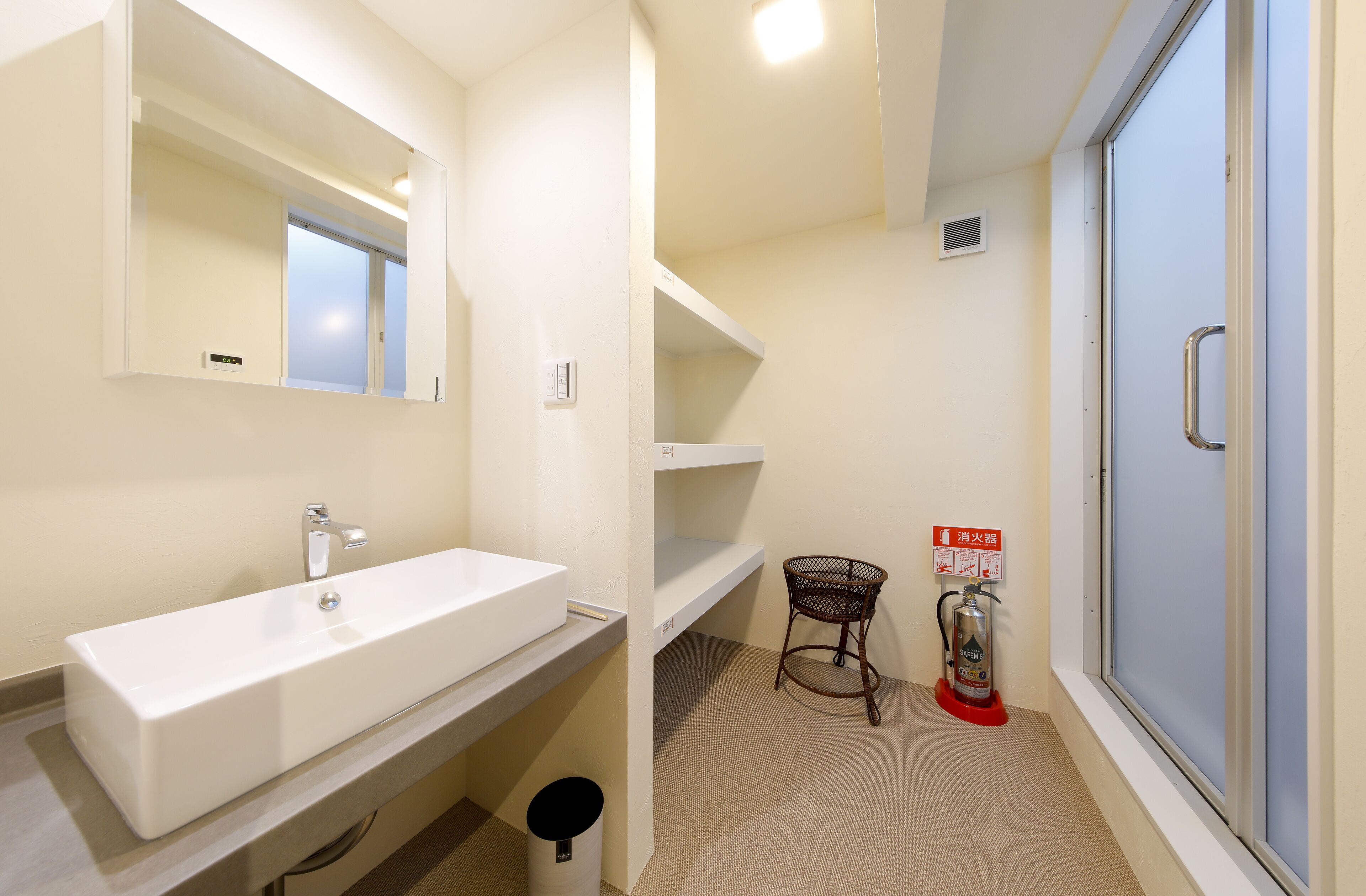 A bathroom with a white sink, mirror, and a fire extinguisher.