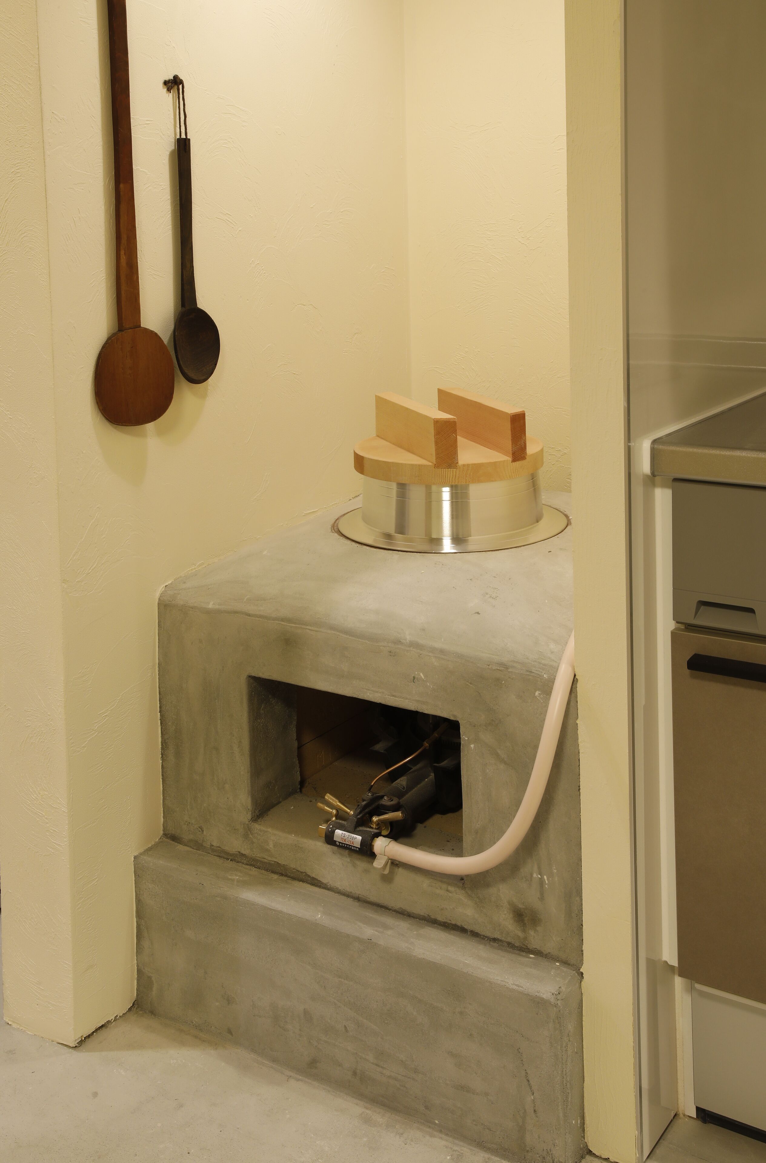 Une cuisine équipée d’une cuisinière intégrée, d’une cuillère en bois, d’une louche et d’une petite étagère en bois.