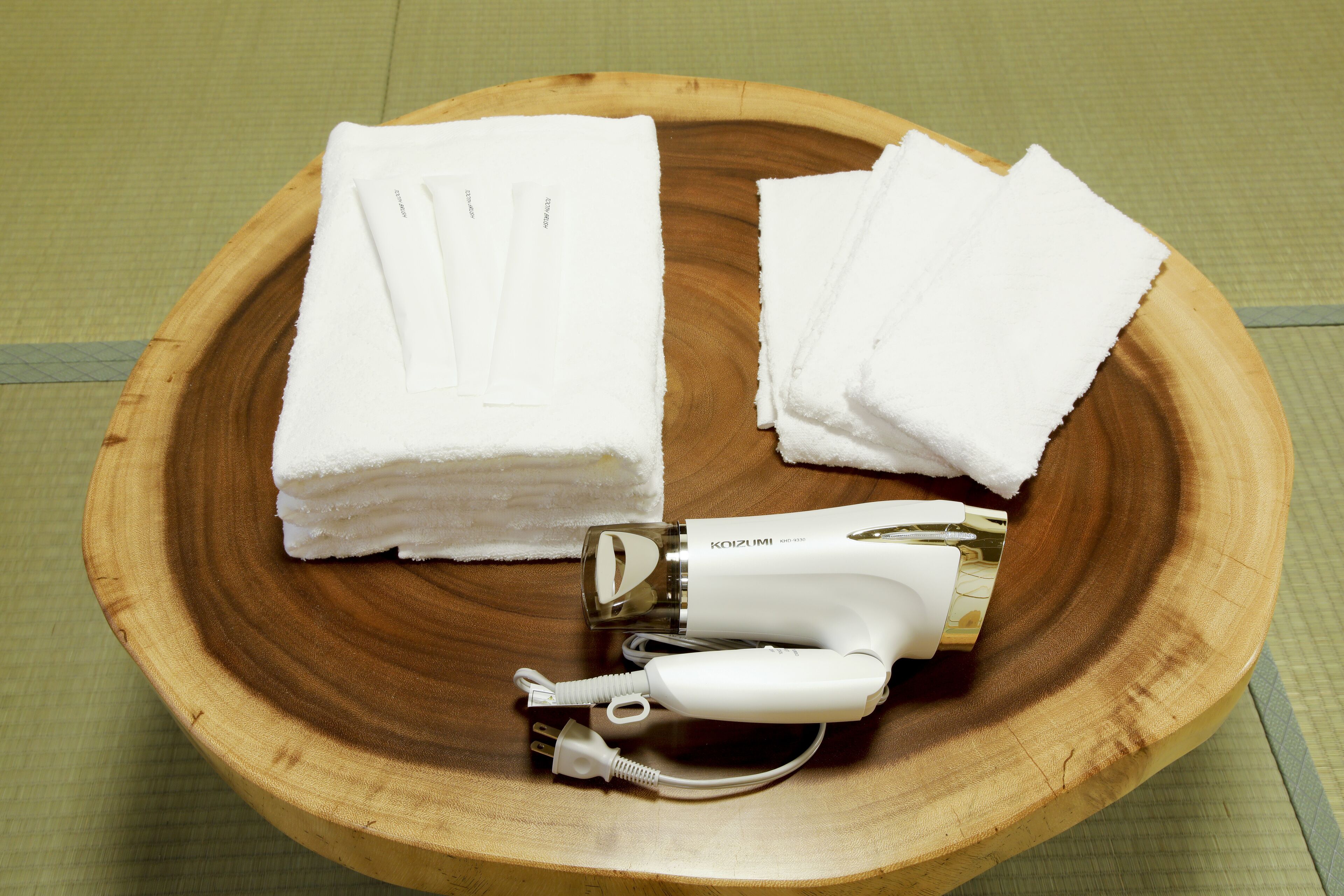 Ein Holztablett mit einem Haartrockner und gefalteten weißen Handtüchern.