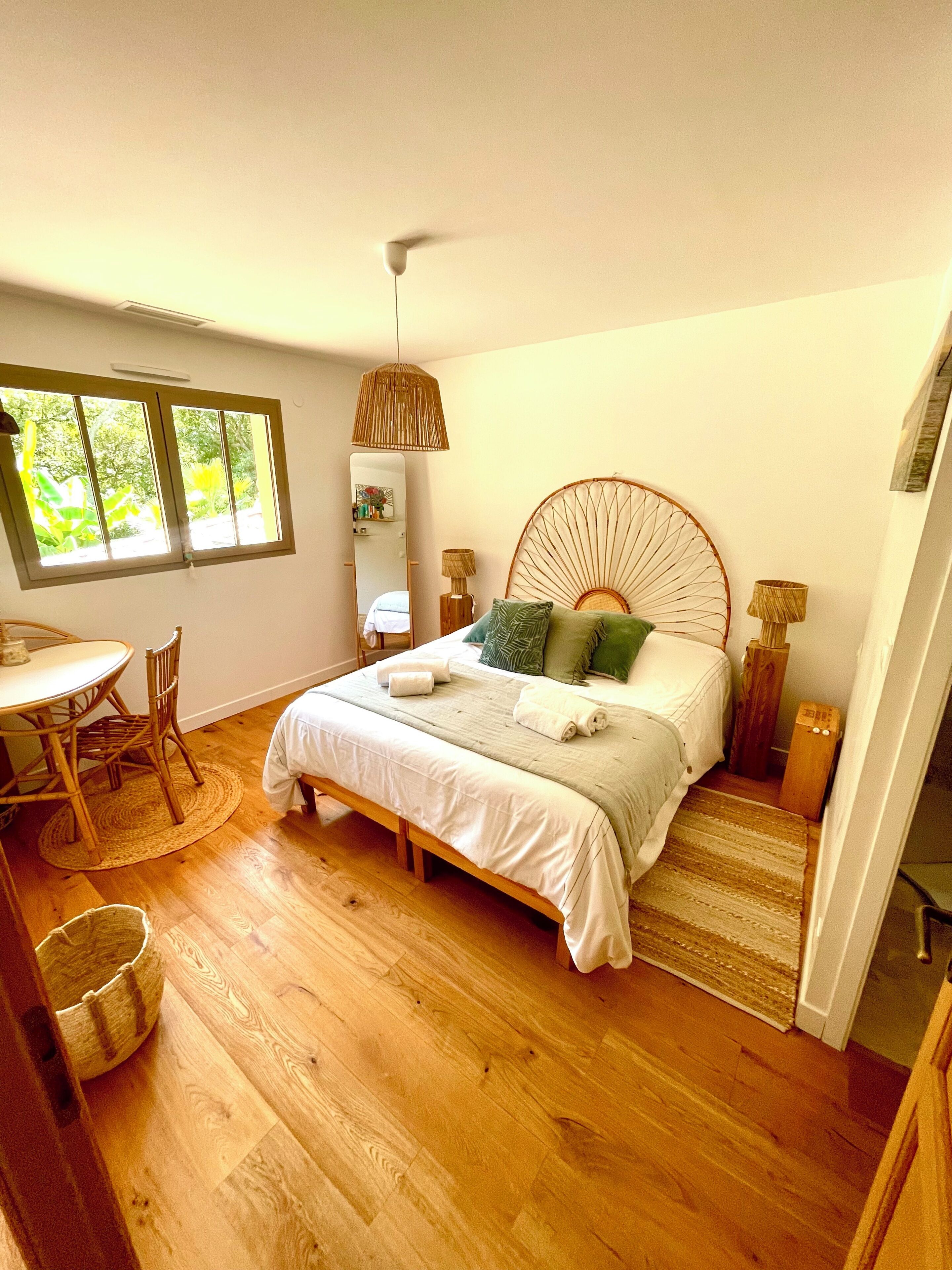 A bedroom with a bed, bedside lamps, a window, a dining table, and chairs.