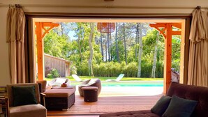 A cozy living room with a view of a pool and lush greenery. - Arcachon, La Hume and Dune du Pyla while enjoying a magnificent maison❤️ (Gujan-Mestras)