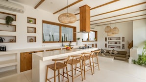 Une cuisine moderne dotée d’un îlot central, de tabourets de bar en bois et de luminaires suspendus.