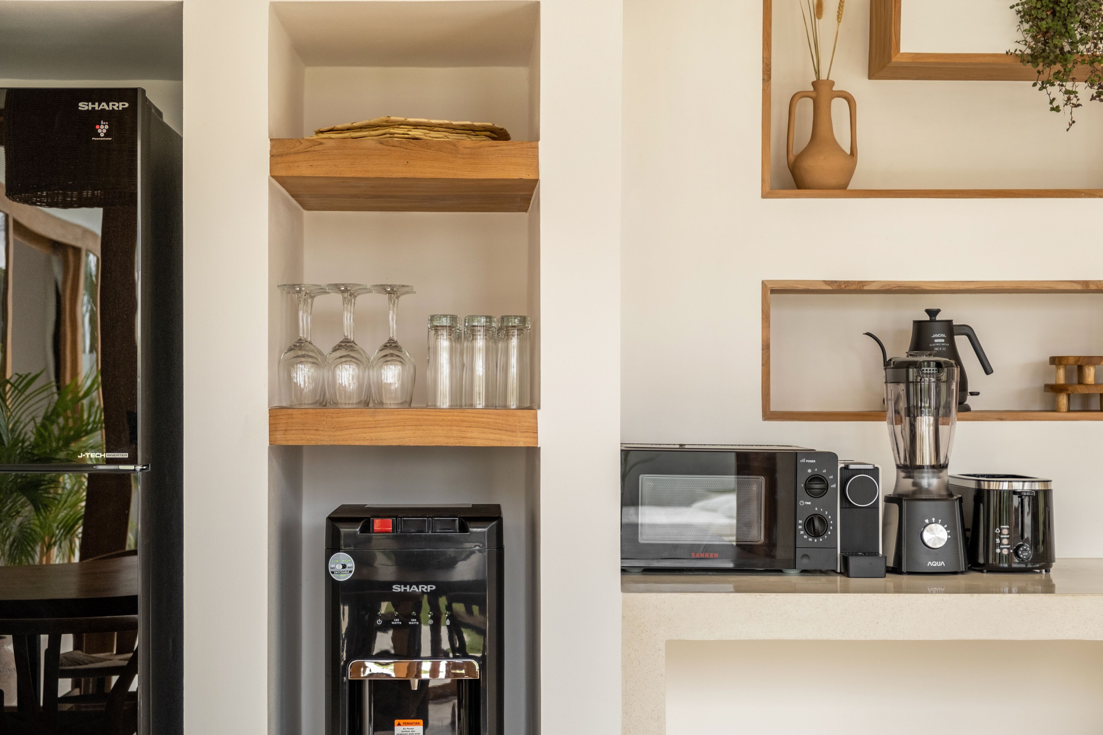 A kitchen with a refrigerator, microwave, coffee maker, and toaster.