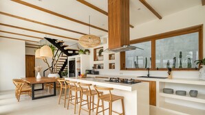 Une cuisine moderne dotée d’un îlot central, de tabourets de bar en bois et d’un escalier menant à un niveau supérieur.