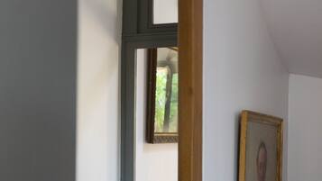 A hallway with a wooden door frame, a framed portrait on the wall, and a patterned floor.