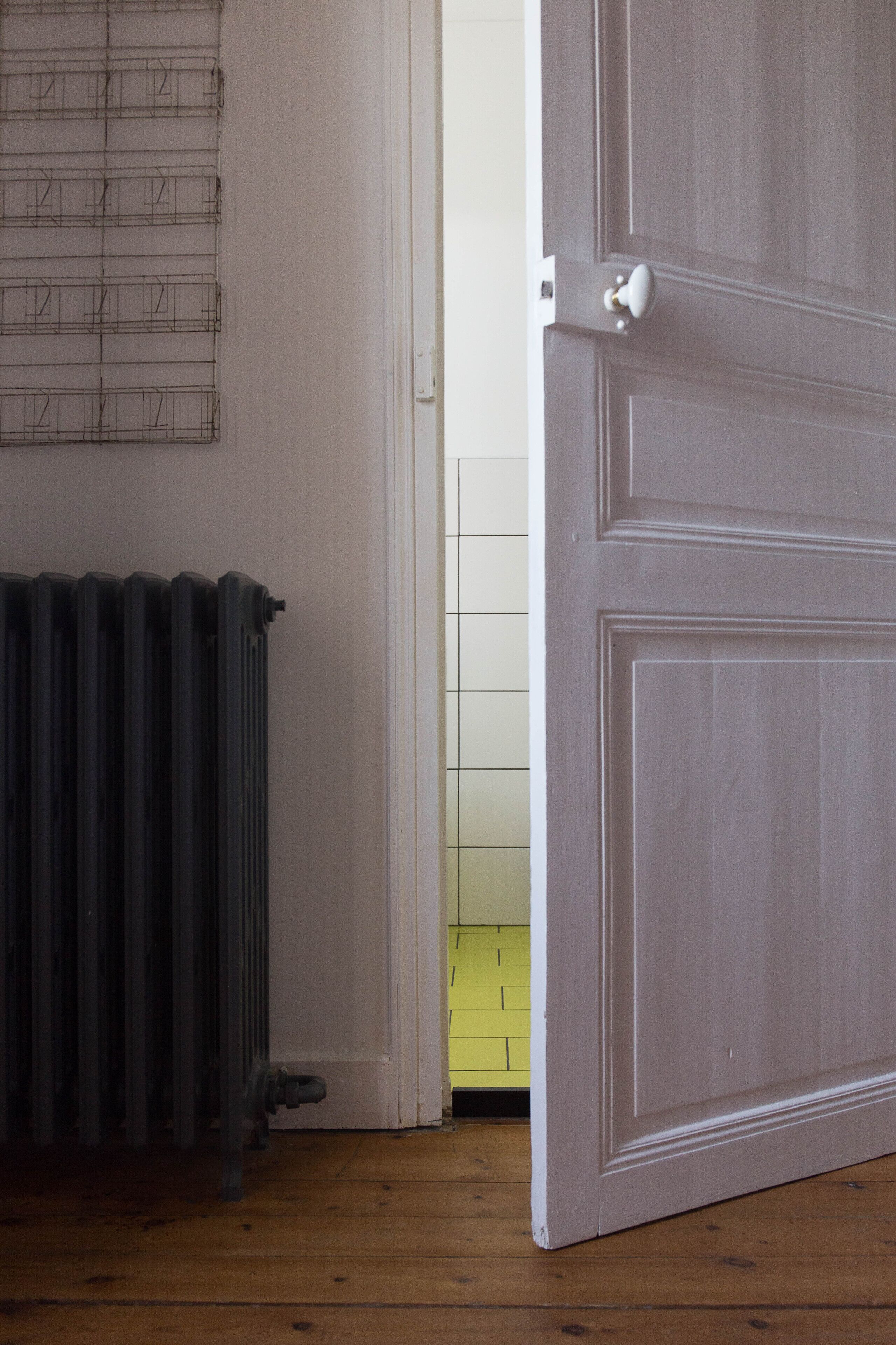 A room with a radiator, a white door, and a yellow wall.