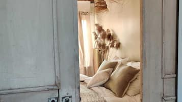 Un dormitorio rústico con techo de madera, cama con ropa de cama estampada y lámparas colgantes tejidas.