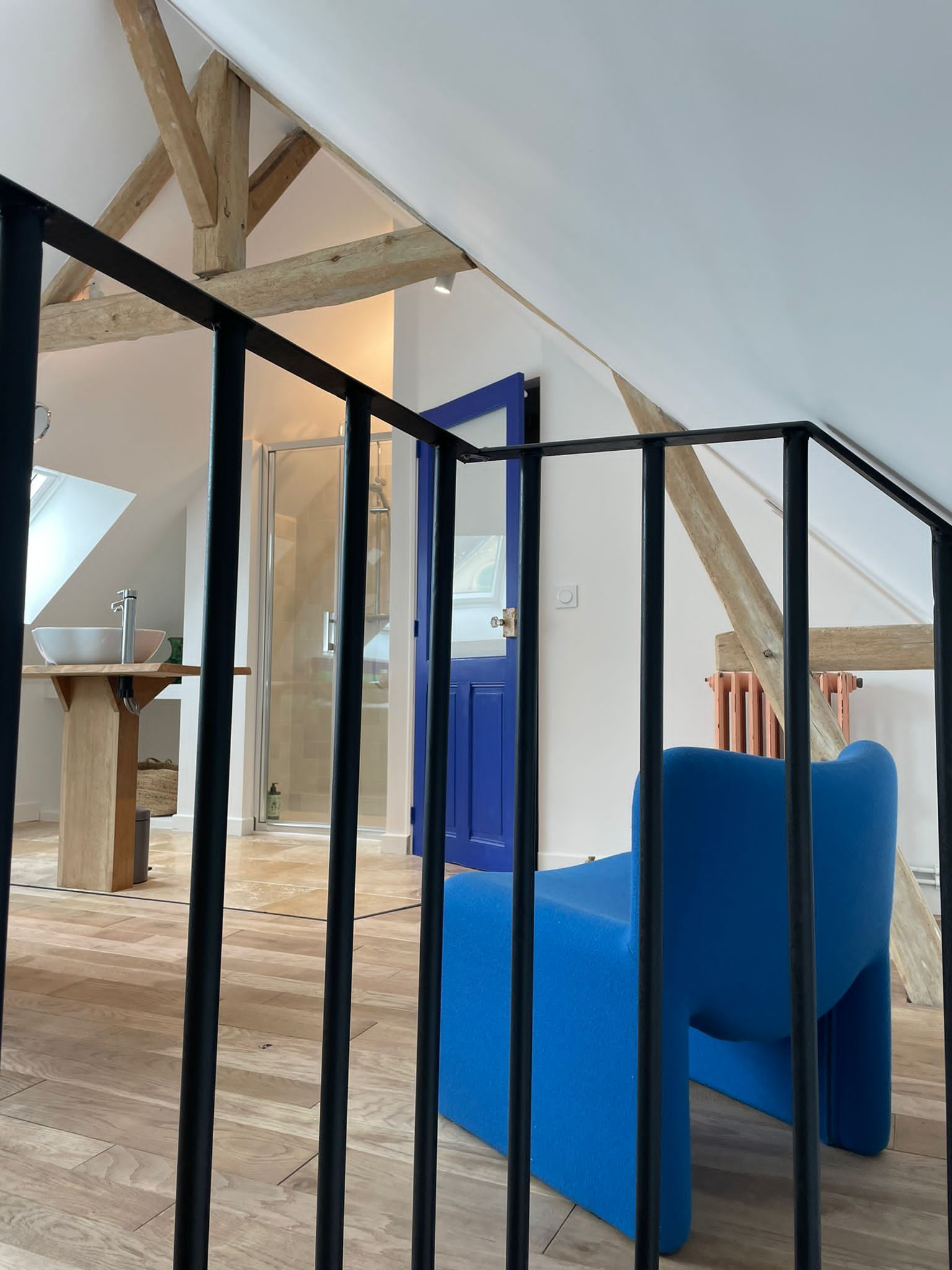 A room with a sloped ceiling, a blue sofa, and a wooden floor.