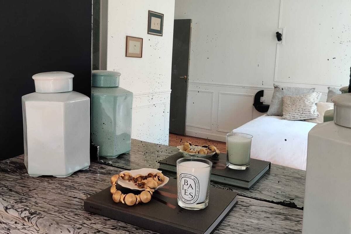 A modern living room with a marble floor, a sofa, a coffee table, and a dining table with a candle and a book.