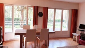 A spacious living room with a dining area, large windows, and a television.