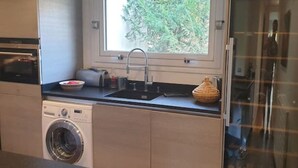A compact kitchen with a built-in washer, a sink, and a window above the counter.