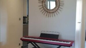 A room with a piano, a wall-mounted mirror, and a ceiling light fixture.