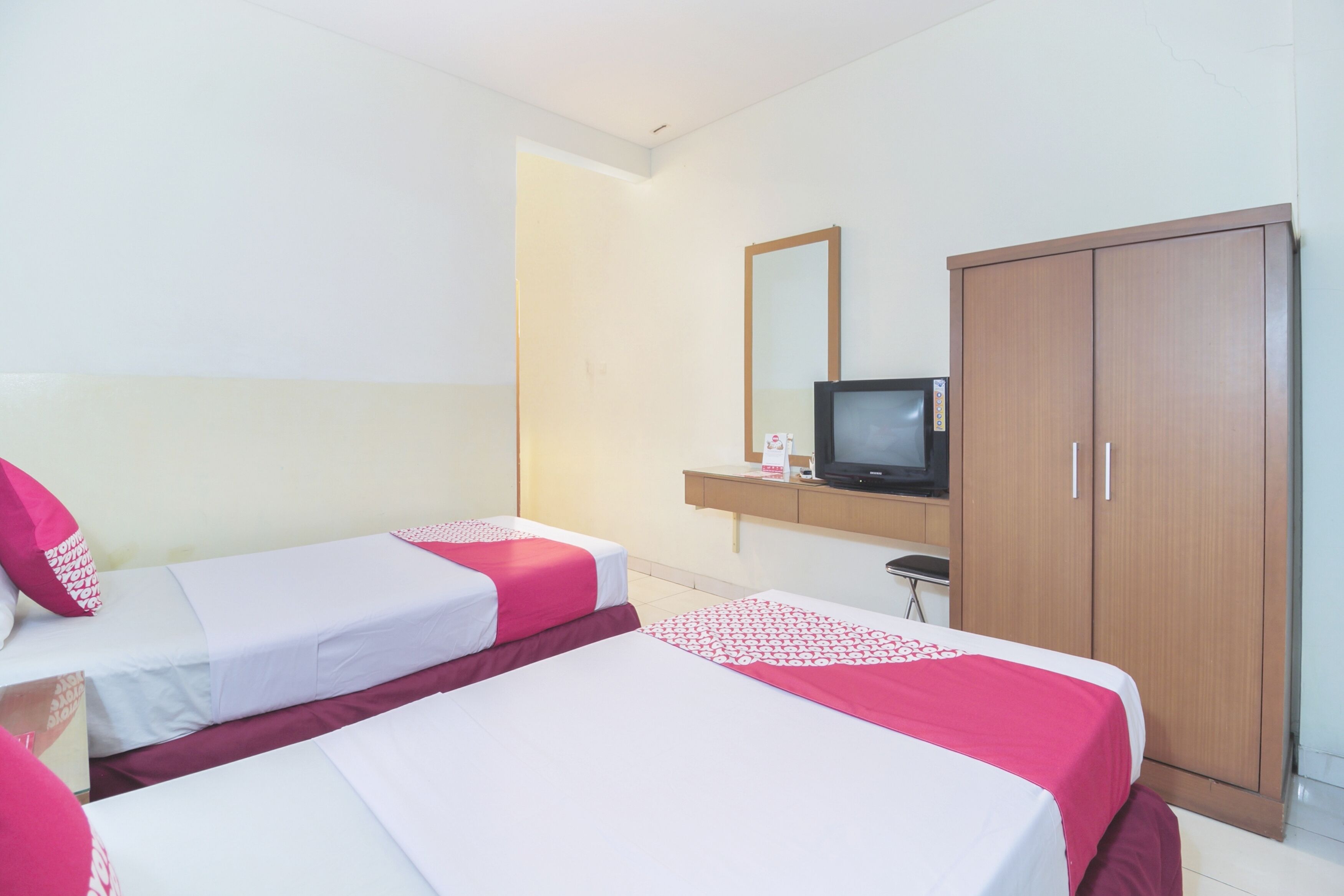 A hotel room with two beds, a TV, and a wardrobe.