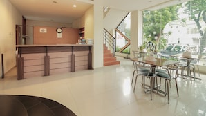 A reception area with a wooden counter, a clock, and a staircase leading to an upper floor. - Capital O Galaxy Inn (Bandung)
