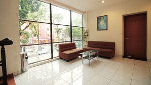 A modern hotel lobby with a large window, a sofa, a coffee table, and a door labeled 201. - Capital O Galaxy Inn (Bandung)