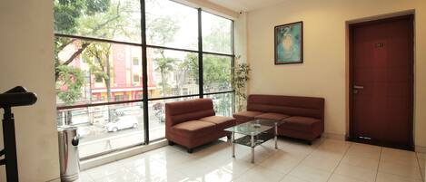 A modern hotel lobby with a large window, a sofa, a coffee table, and a door labeled 201.