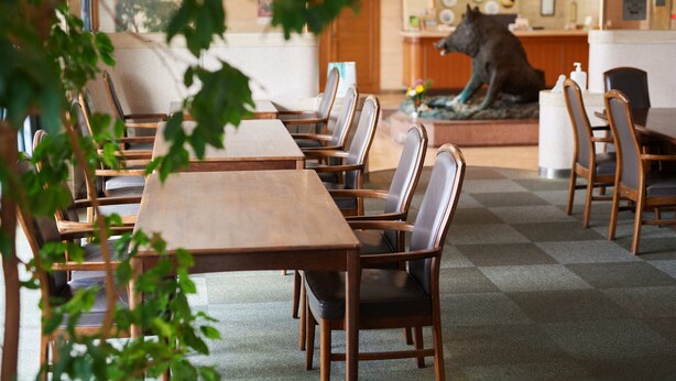 Un restaurante con mesas y sillas de madera, una zona de recepción con una estatua de lobo y un suelo a cuadros.